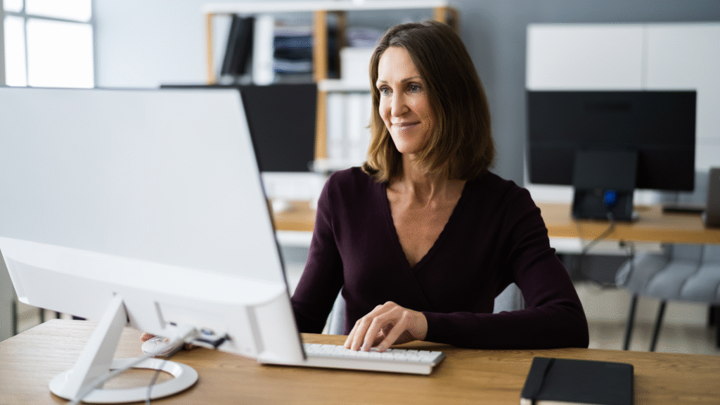 Smiling woman using a desktop computer to search for clinical trial opportunities in Canada.