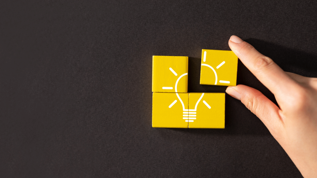 Hand assembling yellow puzzle pieces that form a glowing lightbulb symbolizing understanding and informed consent.